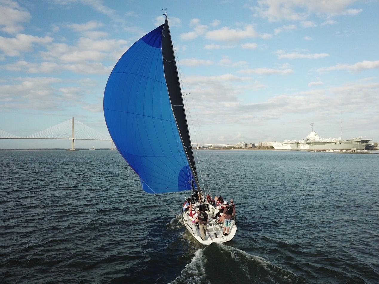 A race boat under a blue spinnaker, crew on deck.