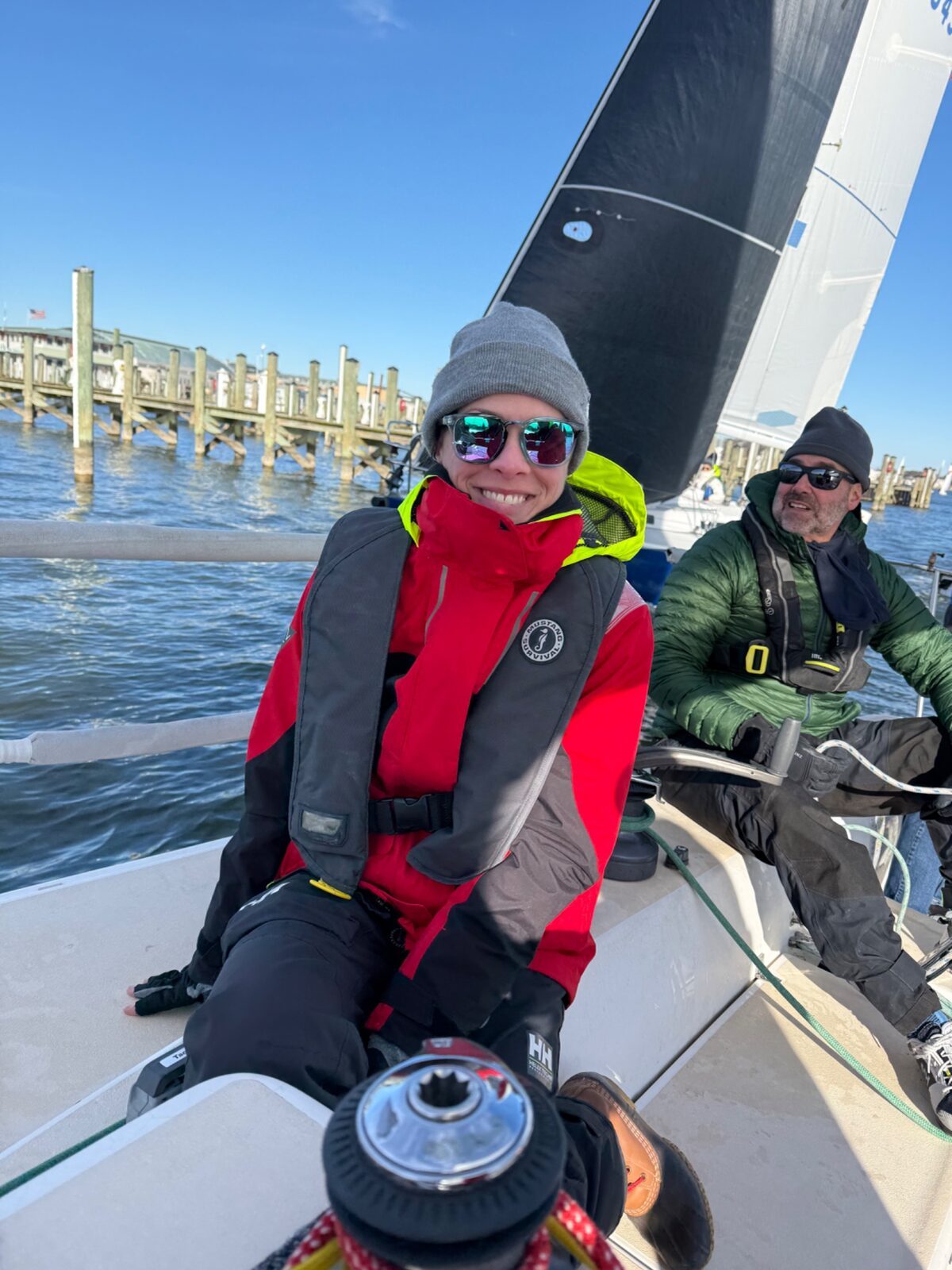 Two sailors in foul-weather gear in the cockpit of a race boat.