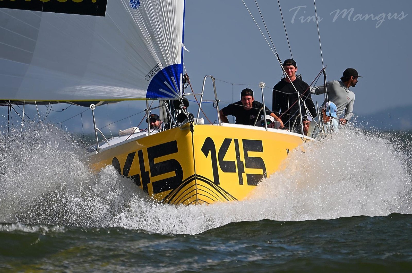 An offshore race boat under a yellow spinnaker.