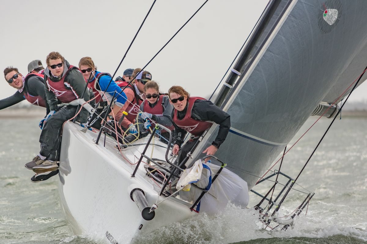 A college sailing team hiking hard on a Melges 24 in a breeze.