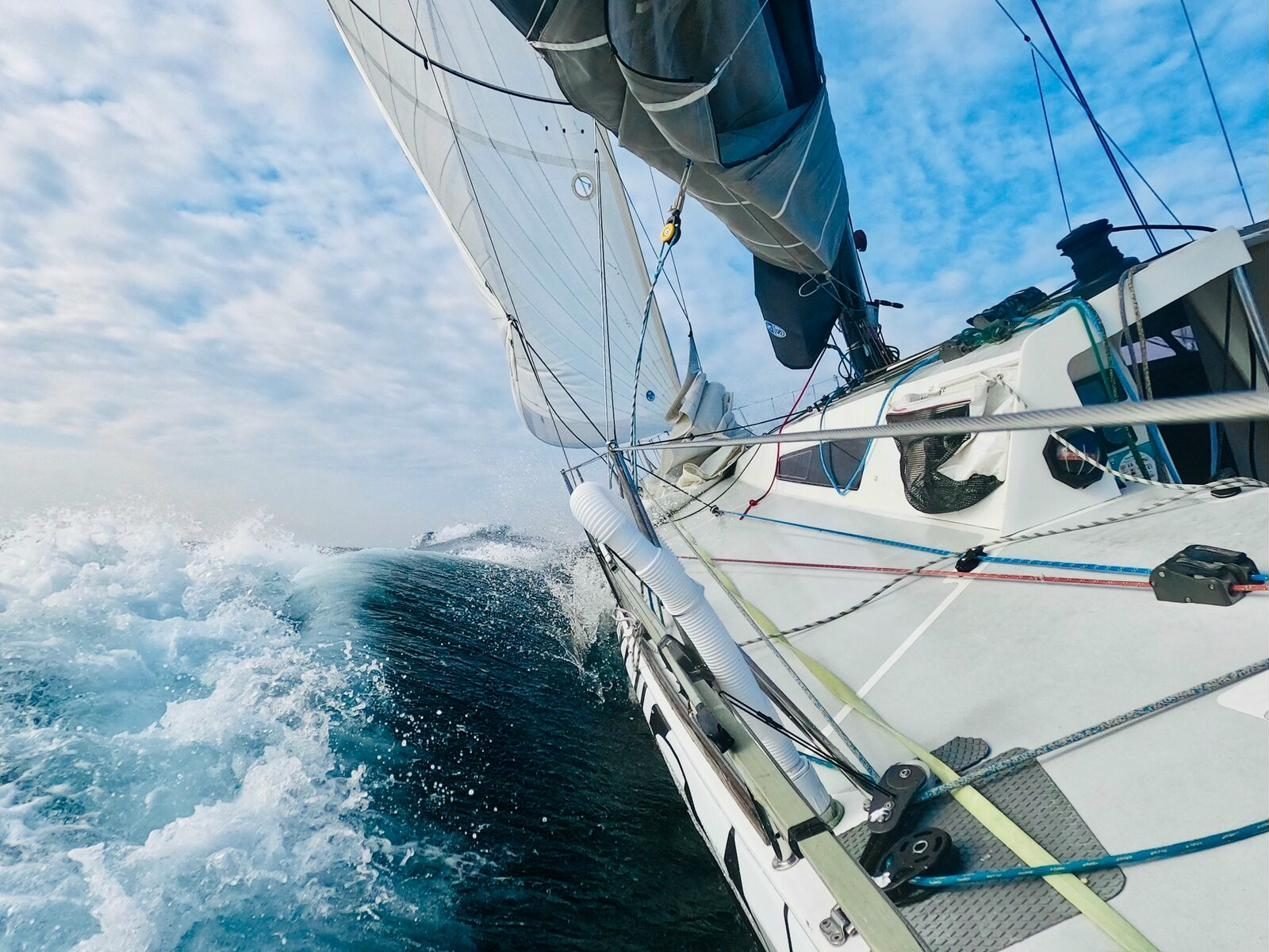A race boat heeled and driving offshore, bow wave breaking.